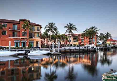 Sunrise over a harbor with sailboats and colorful buildings