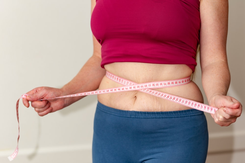 Woman measuring her waist for weight loss purposes when starting semaglutide