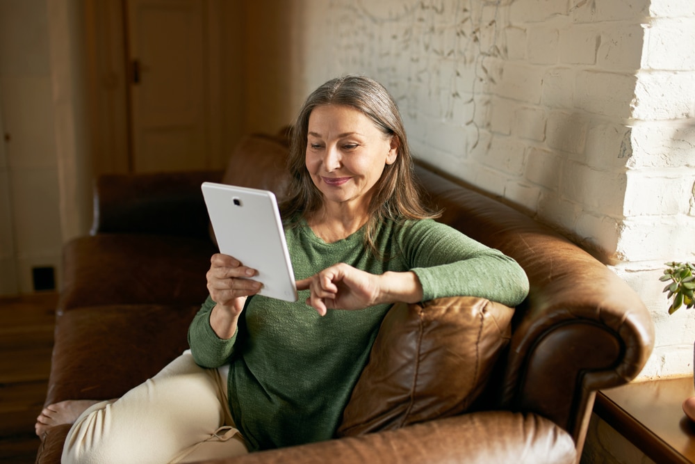 Older woman reading on tablet to keep her brain smart.