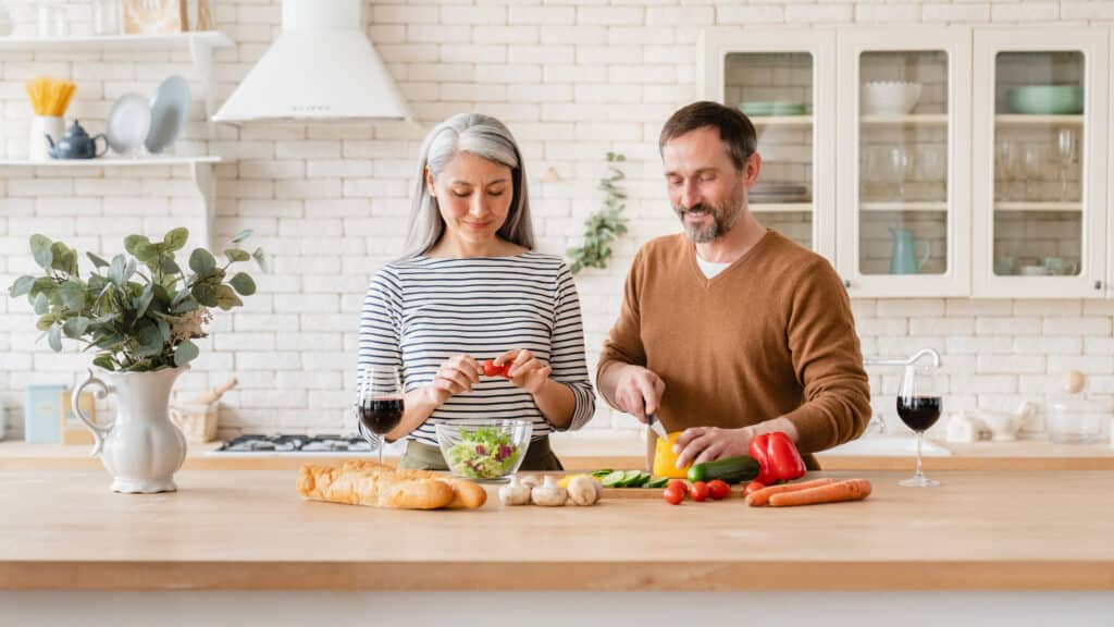 Middle-aged couple preparing fresh vegetables and salad together to support healthy aging and reduce inflammation