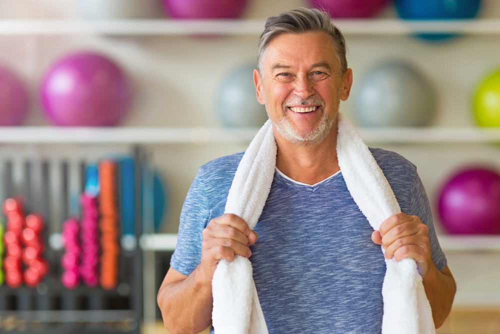 Middle-aged man smiling and energetic at the gym after a workout.