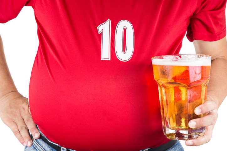 Man with visible belly holding a beer, illustrating alcohol’s effect on weight gain