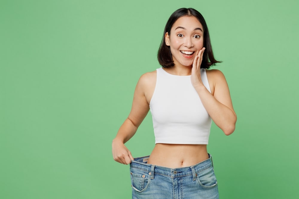 Excited woman in jeans that are too big after weight loss