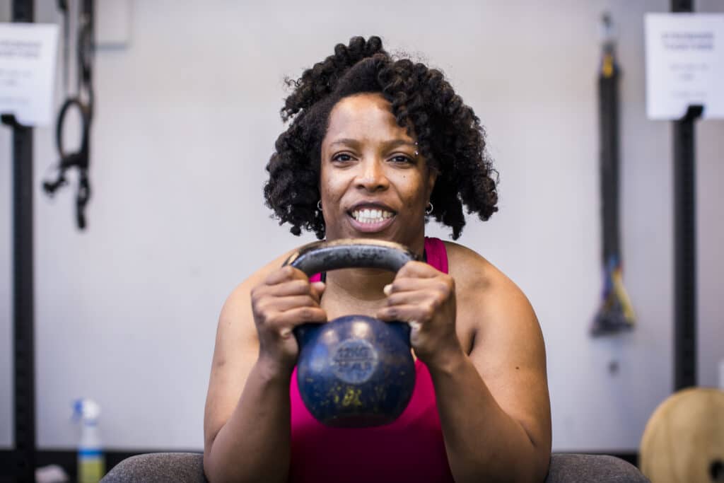 Mature woman lifting kettle bell at the gym to build muscle and protect her body as she ages.