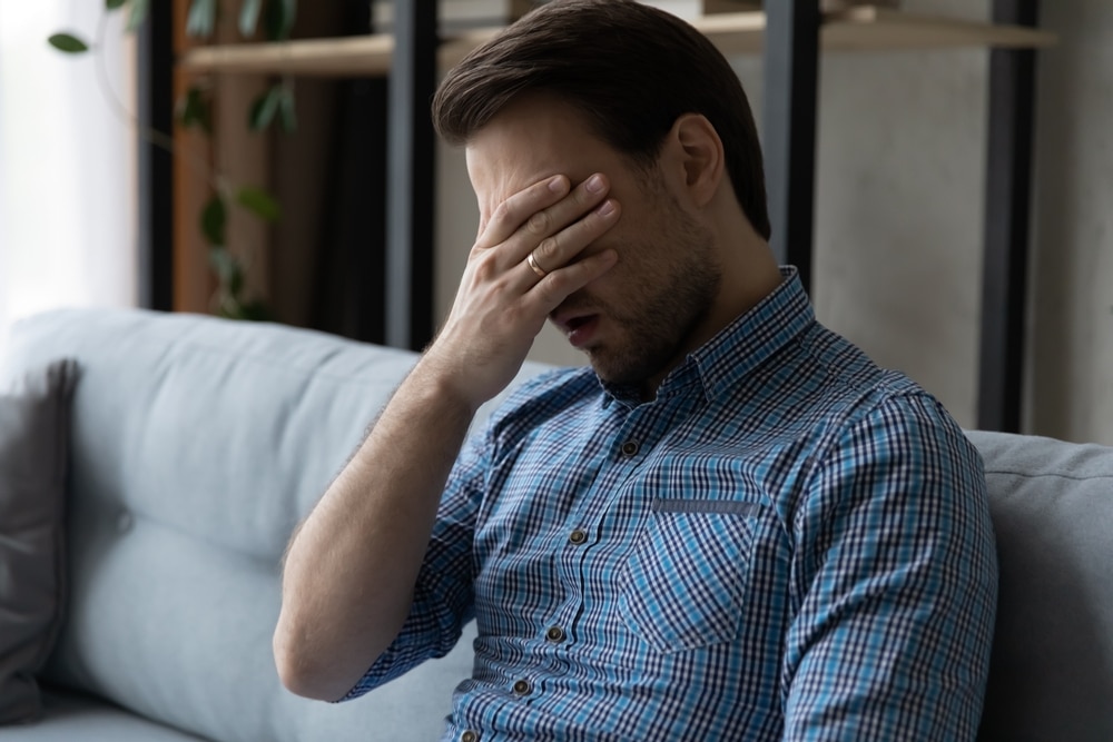 Man sitting on a couch looking fatigued and stressed