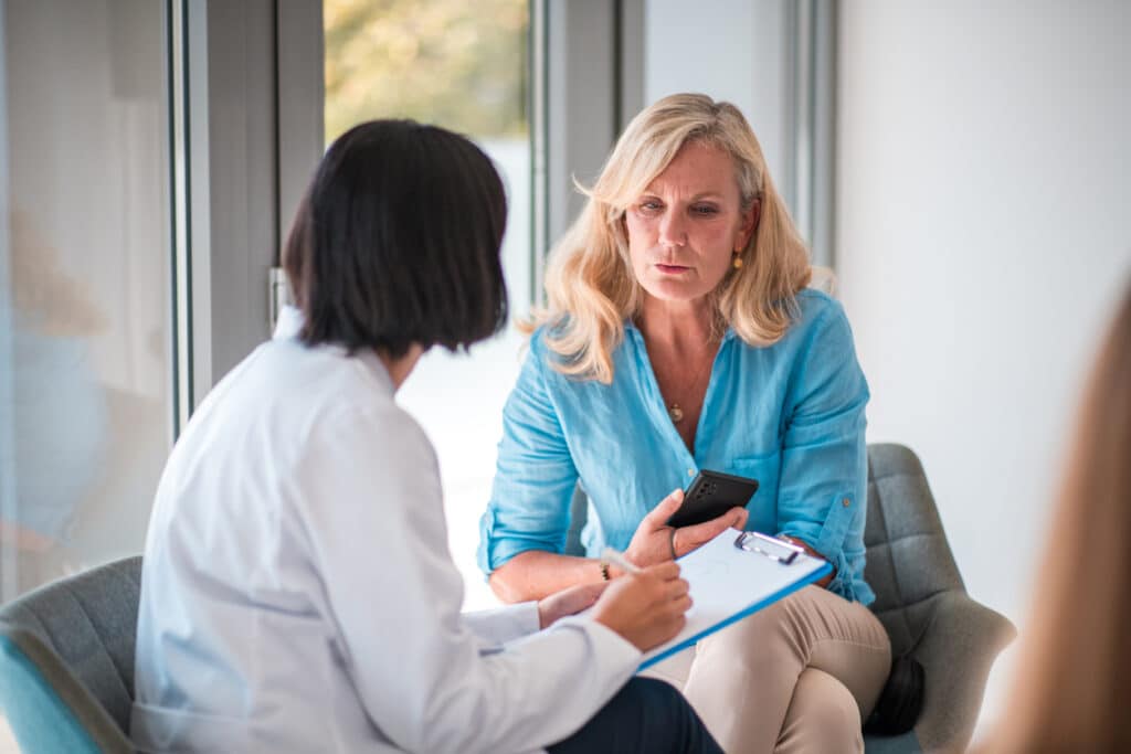 Woman discussing menopause symptoms and intimate health concerns with a medical provider during a consultation.