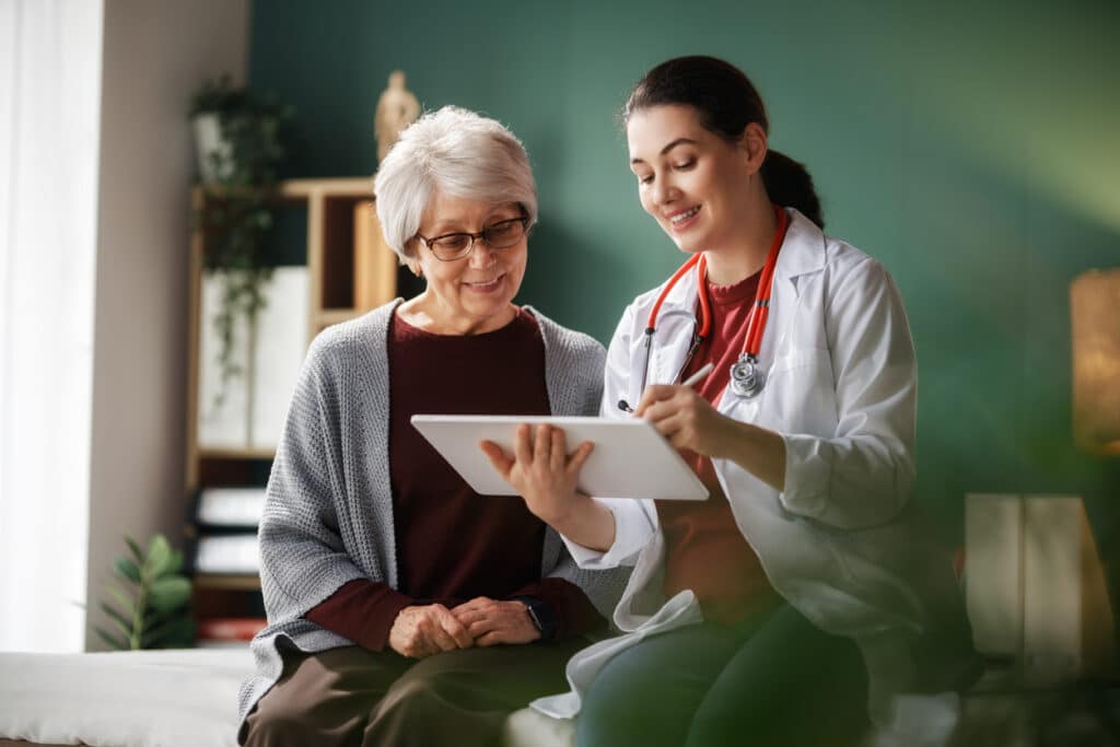 Doctor reviewing health information with an older patient on a tablet.