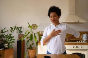 Woman holding her chest while experiencing possible heart palpitations during menopause